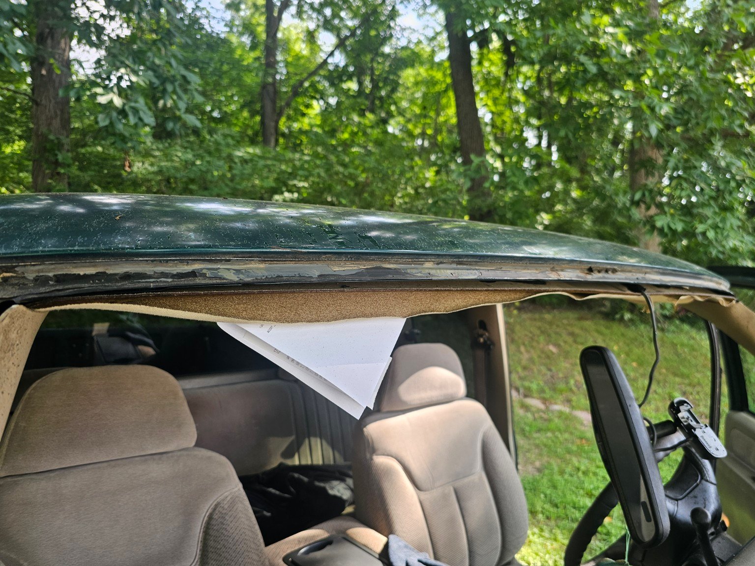 Exposed vehicle windshield opening photographed by Auto Glass Xpress after removing a prior windshield, with corrosion visible along the pinchweld